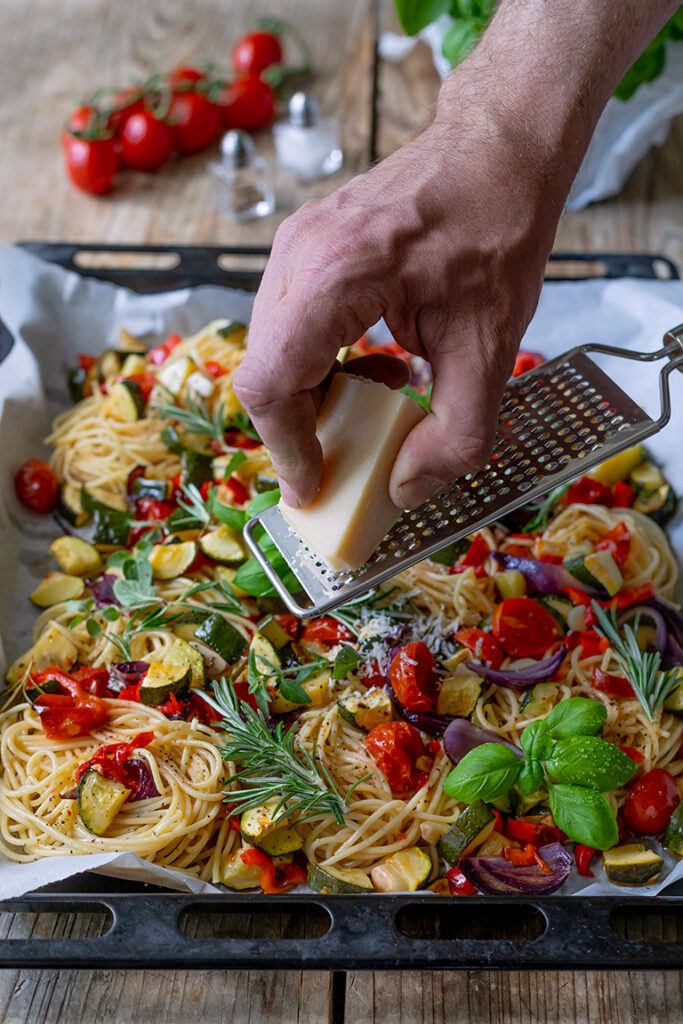 Parmesan wird über die Pasta mit Ofengemuese gerieben und von Foodfotografin Verena Pelikan fotografiert