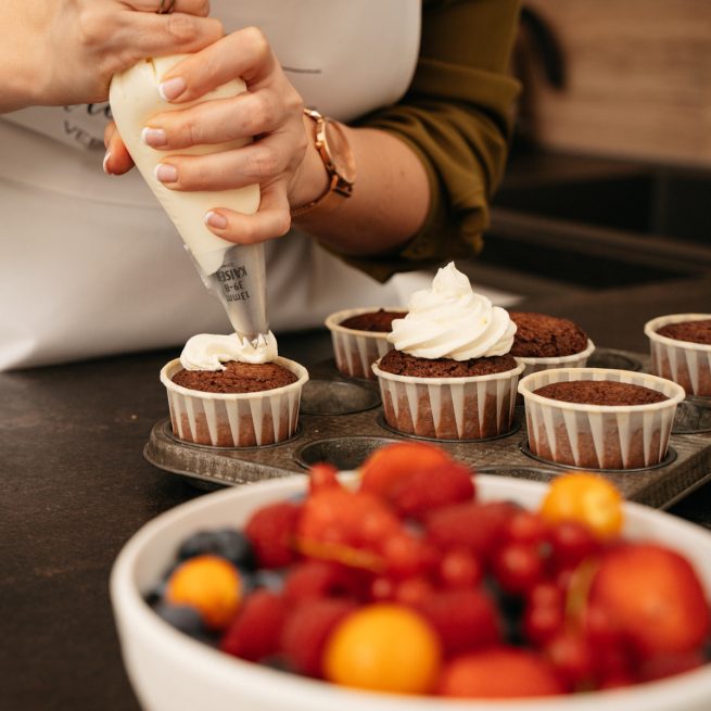 Cremehaeubchen wird auf den Kuchen beim Cupcake Backkurs im Kochstudio SchlossStudio im Weinviertel in Niederoesterreich aufdressiert