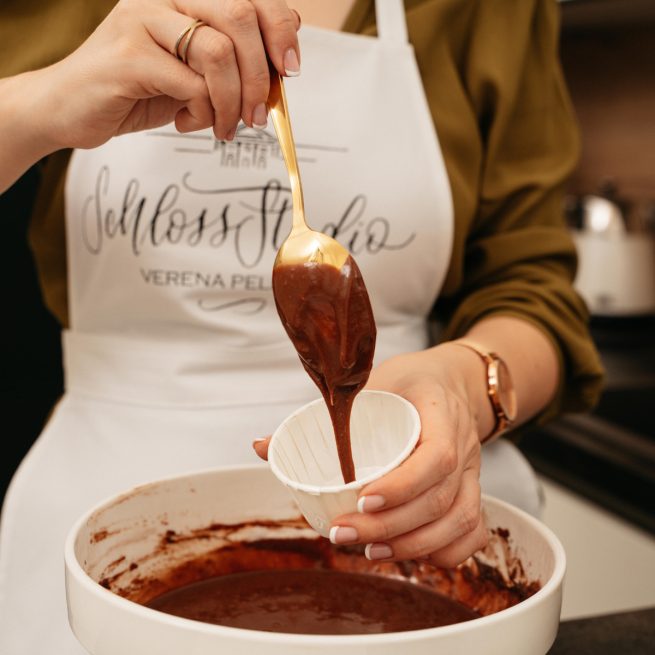 Schokoladeteig wird in Muffinfoermchen gefuellt beim Cupcake Backkurs im Kochstudio SchlossStudio im Weinviertel in Niederoesterreich