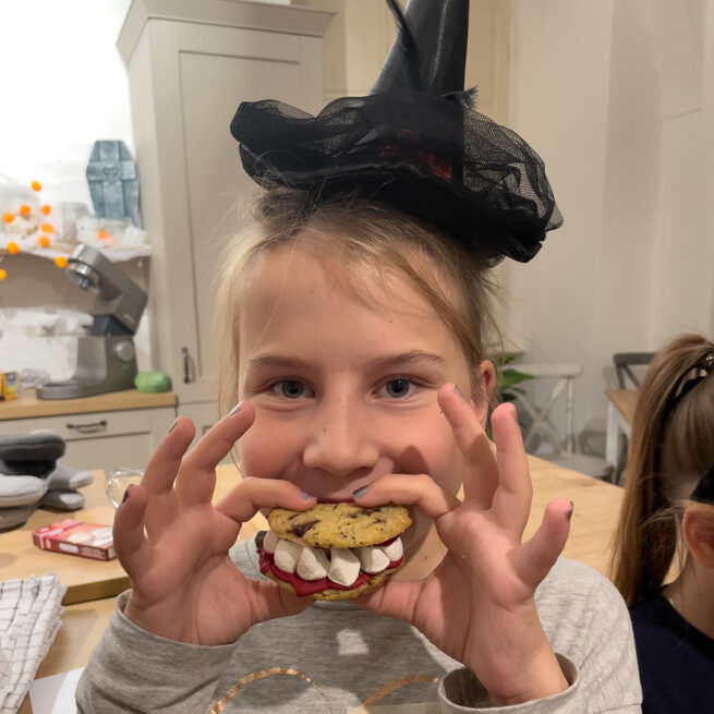 Begeistertes Kind beim Halloween Kinderbackkurs mit selbst gemachten Gebisscookies im Kochstudio SchlossStudio