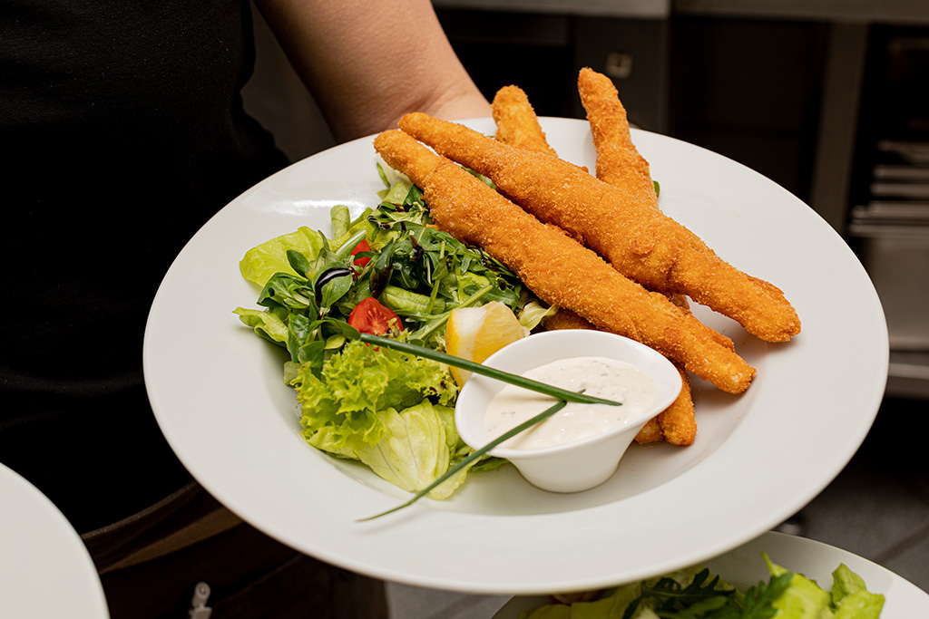 Teller mit Spargel Cordon Bleu in der Hand der Kellnerin im Gasthaus Kraft von Foodfotografin Verena Pelikan